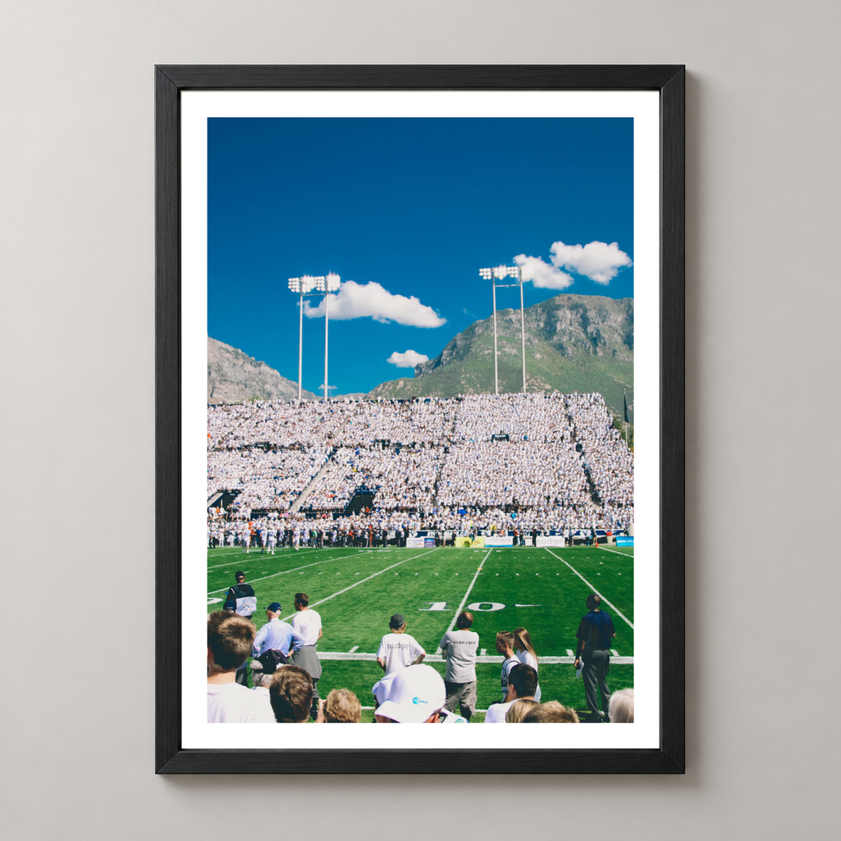 Vibrant Football Stadium with Mountain Backdrop - High-Quality Print — realistic black frame studio view with white border