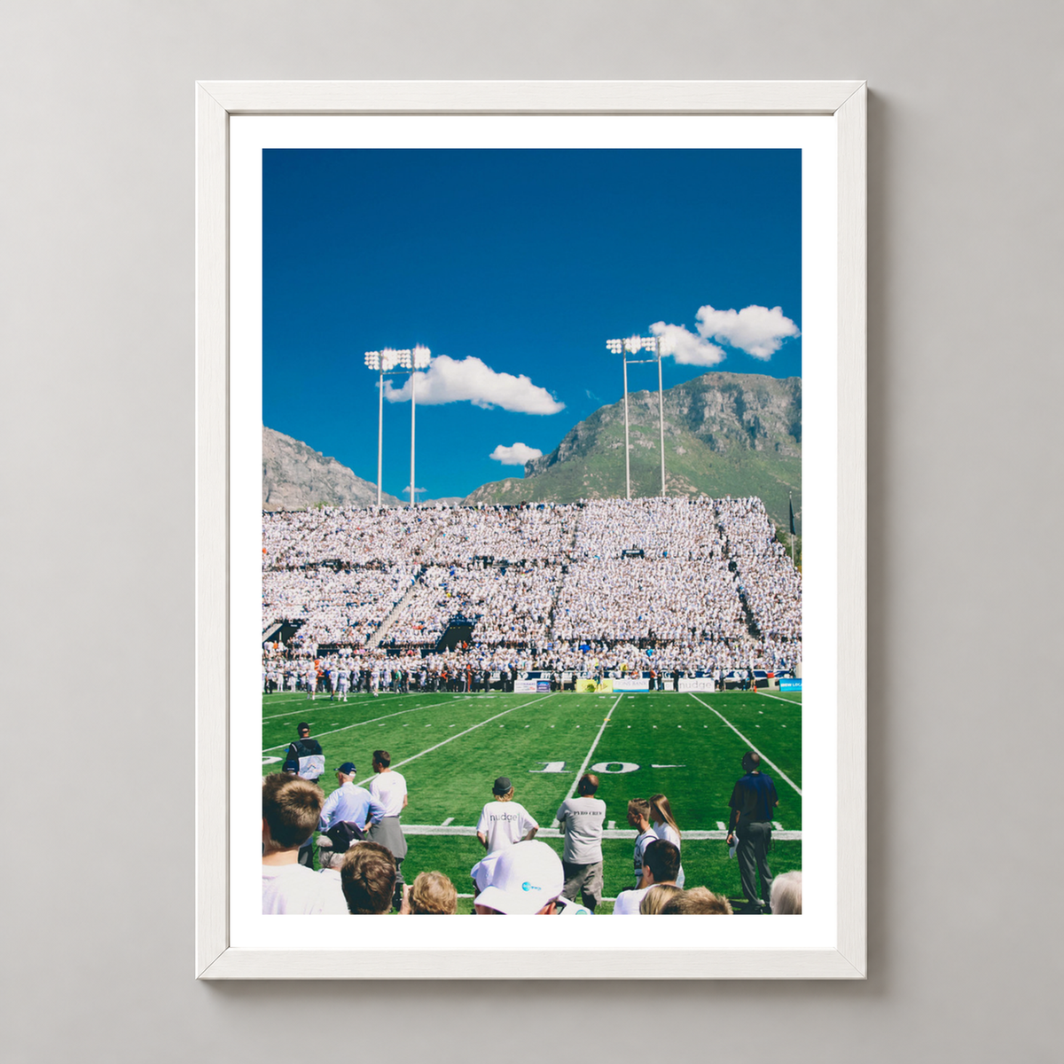 Vibrant Football Stadium with Mountain Backdrop - High-Quality Print — realistic white frame studio view with white border