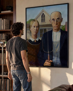 American Gothic Art Print by Grant Wood in a black frame; styled man setting.