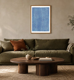Blue Checkerboard in a natural wood frame above an olive sofa; styled living-room mockup