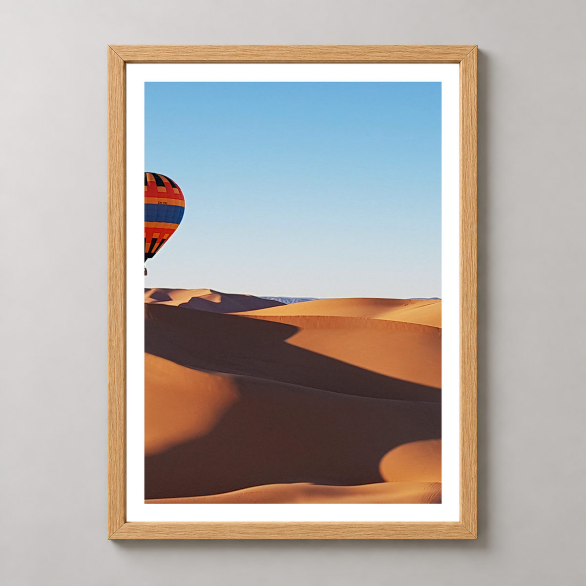 Vibrant Hot Air Balloons Over Desert Landscape Art Print — realistic natural wood frame studio view with white border