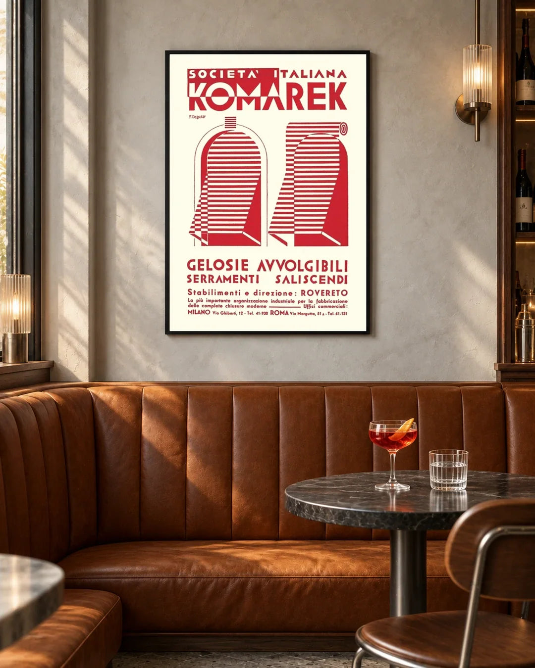 Komarek Italian Advertising Poster by Fortunato Depero — black frame in a contemporary bar with grey walls and tan leather seating