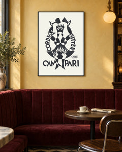 Campari Black and White Toasting Figure Poster — black frame in a warm bistro dining space