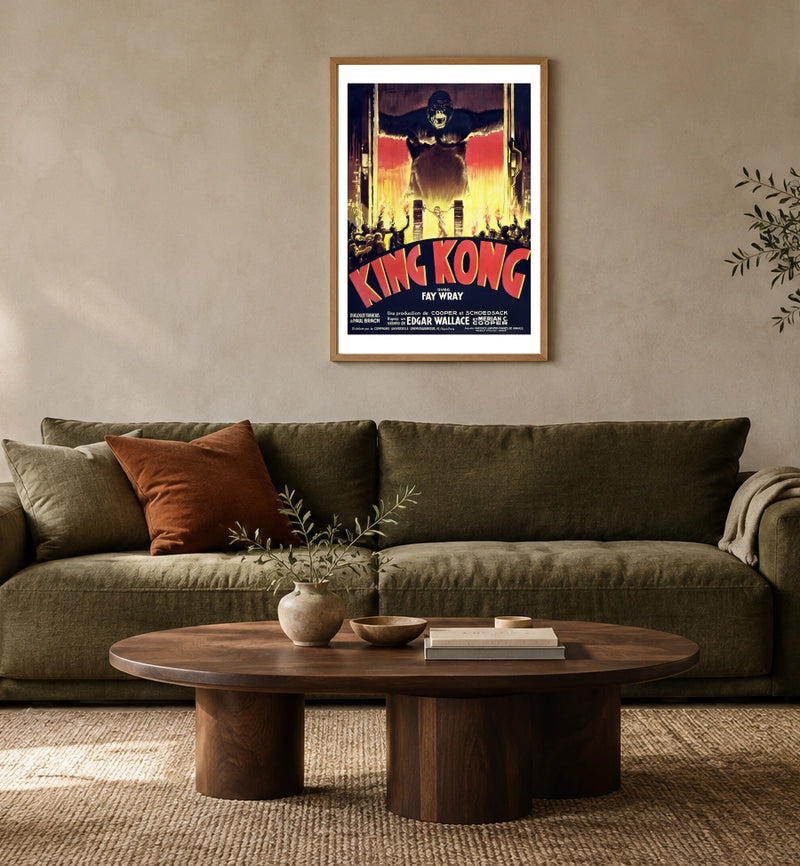 King Kong — French Poster in a natural wood frame above an olive sofa; styled living-room mockup