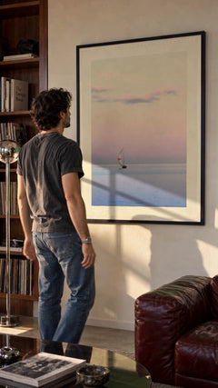 Pastel Sailing in a black frame being hung on a wall; styled scene