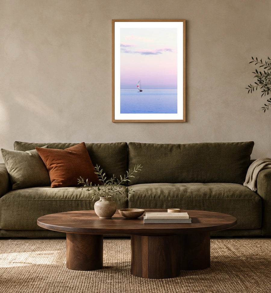 Pastel Sailing in a natural wood frame above an olive sofa; styled living-room mockup