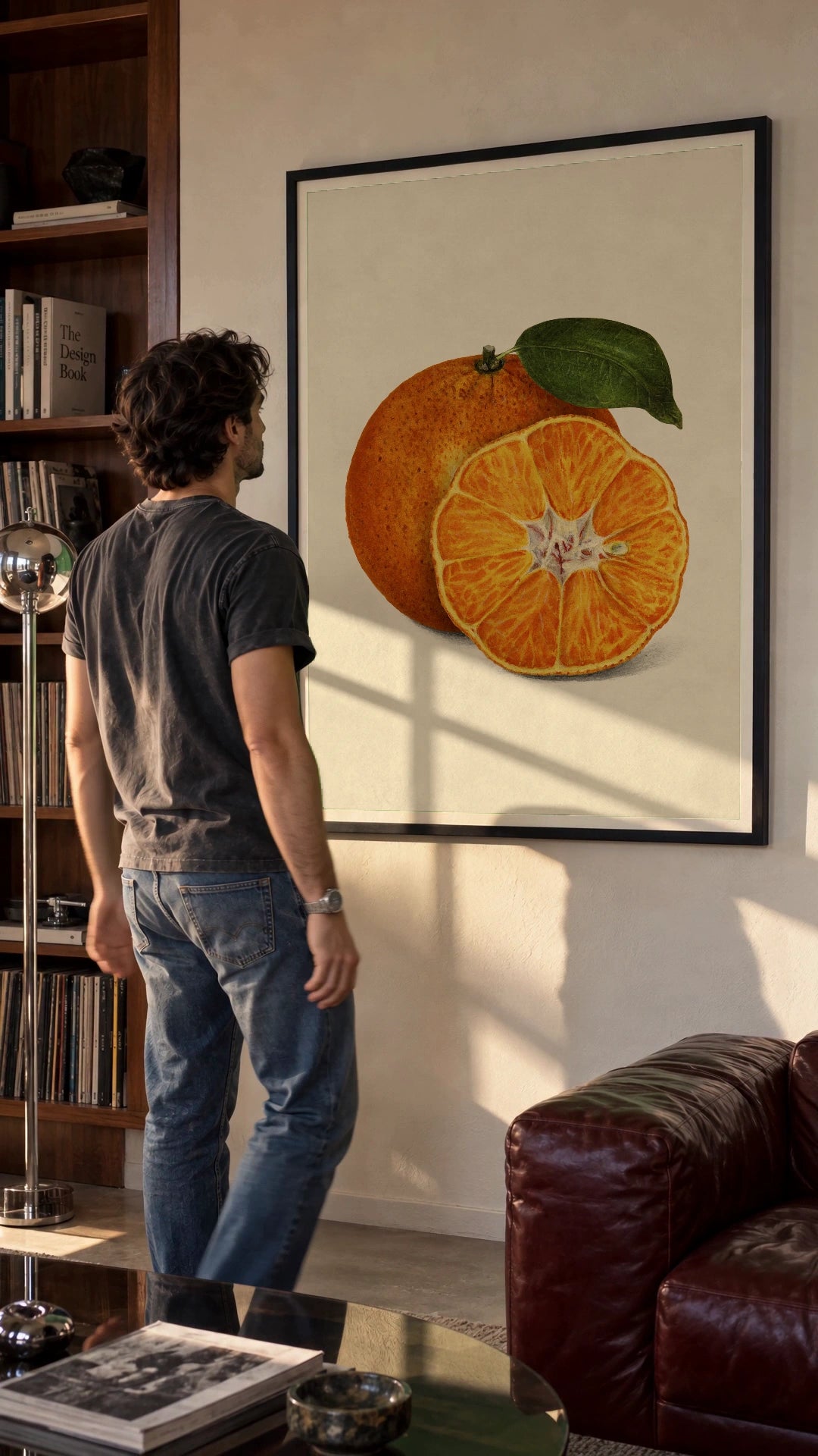 Tangerine Study in a black frame being hung on a wall; styled scene