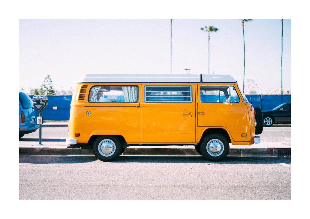 Yellow Van Coastal Photographic Print. A bright yellow van sits beneath a pale sky, with palm trees rising behind it